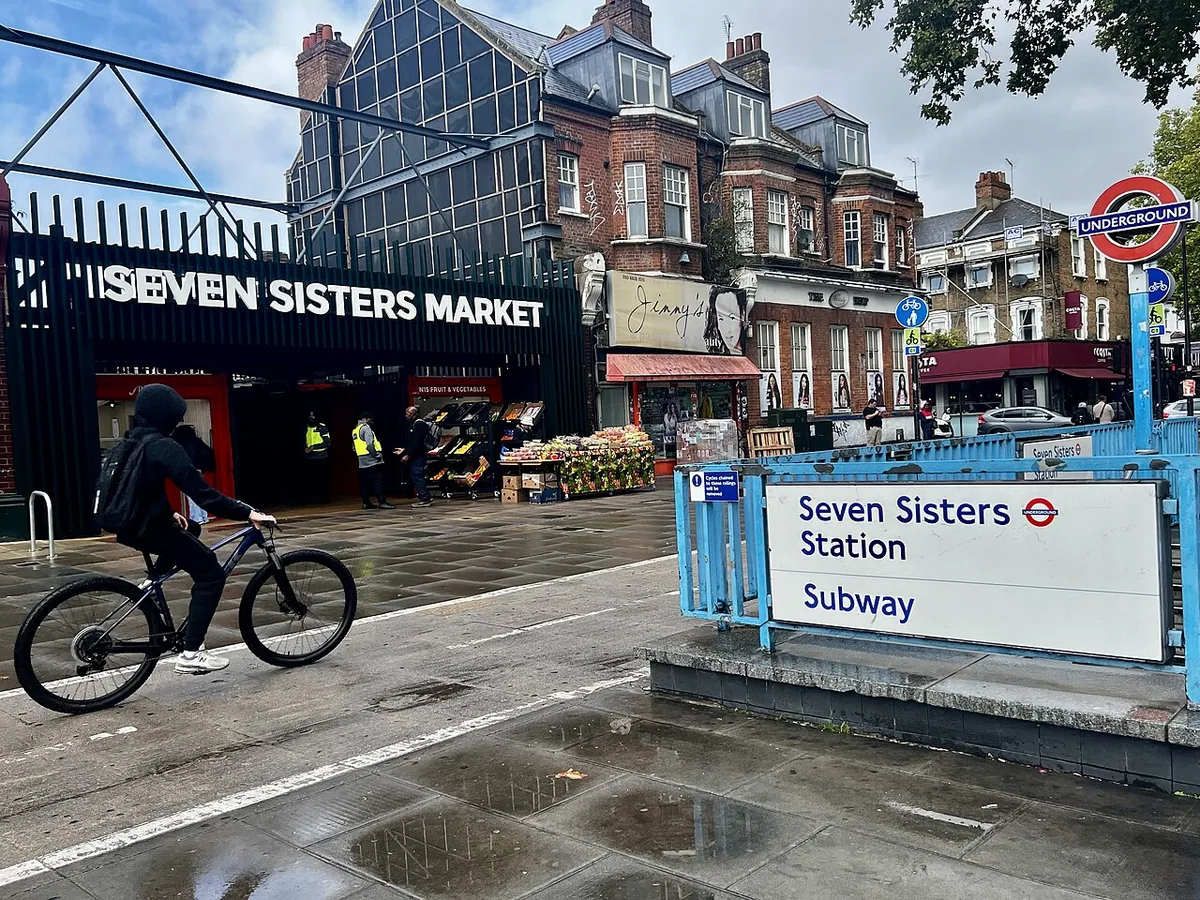 A cyclist passes between Seven Sisters Market and Seven Sisters tube station